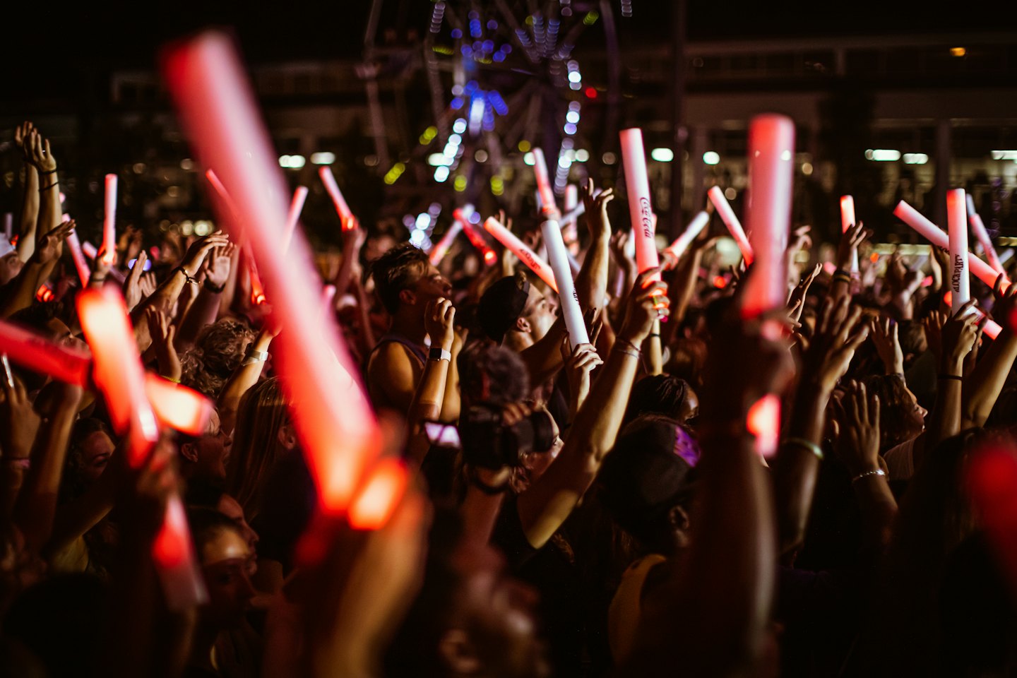 Crowd of people waving glowing red light sticks at night.